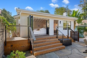 A modern house with a wooden deck, a staircase, and a white interior.