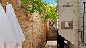 A wooden wall with a white towel hanging, a shower area with a handheld showerhead, and a small window with two lights. - Humphrey House | Walk to Beach, Coast Village Rd, 3 En Suite Bedrooms (Montecito)