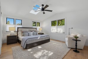 Ein Schlafzimmer mit Bett, Nachttischen, Deckenventilator und Fenstern.