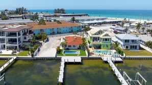 A coastal hotel with multiple buildings, a swimming pool, and a dock. - Manatee Cove -3-bedroom bayfront home with dock (Bradenton Beach)