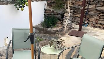 A patio area with two chairs, a small table, and a stone wall backdrop.