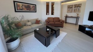 Una sala moderna con sofá, sillón, una mesita de centro y una planta en maceta.