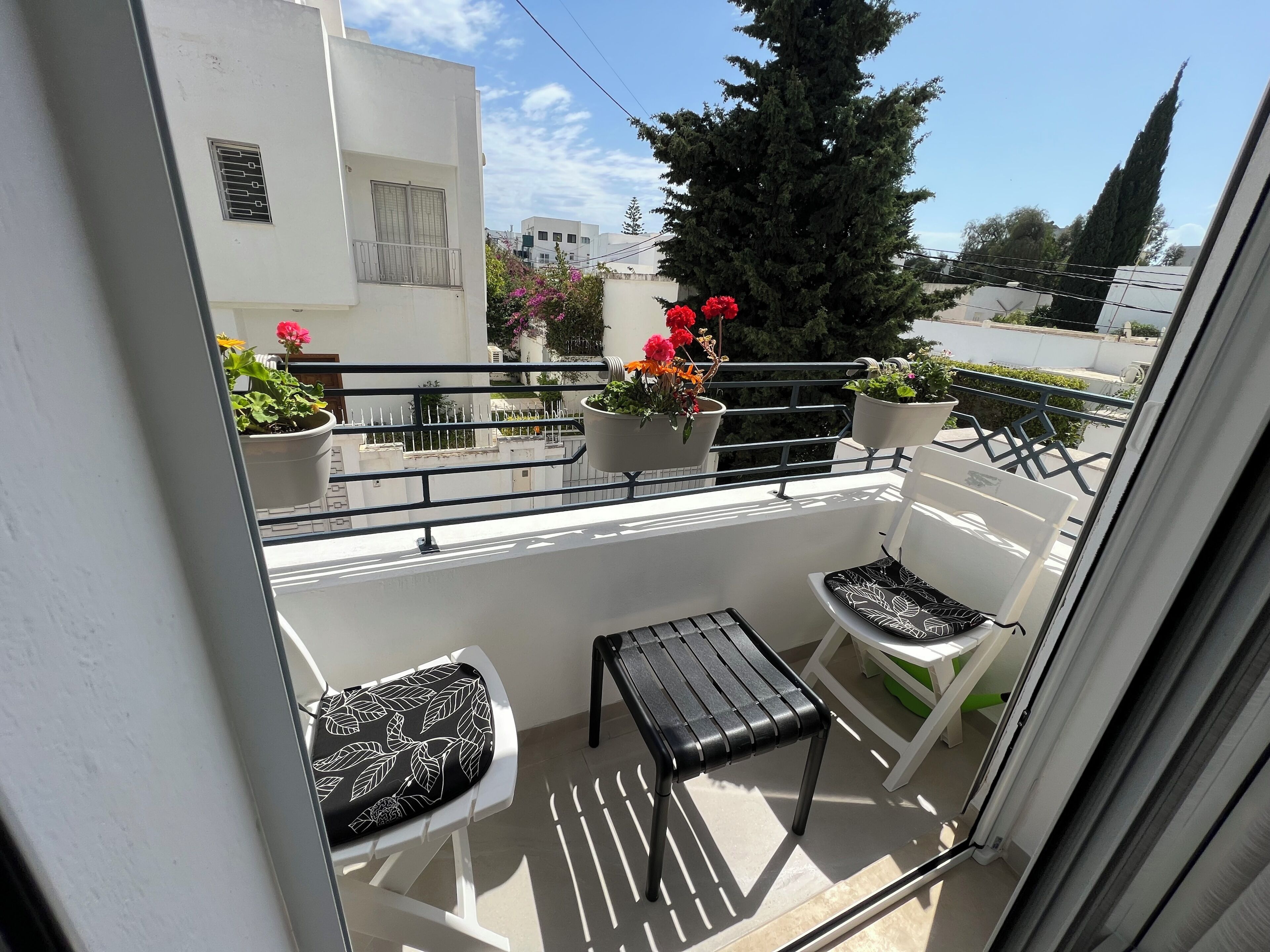 A balcony with two chairs, a small table, and potted plants.