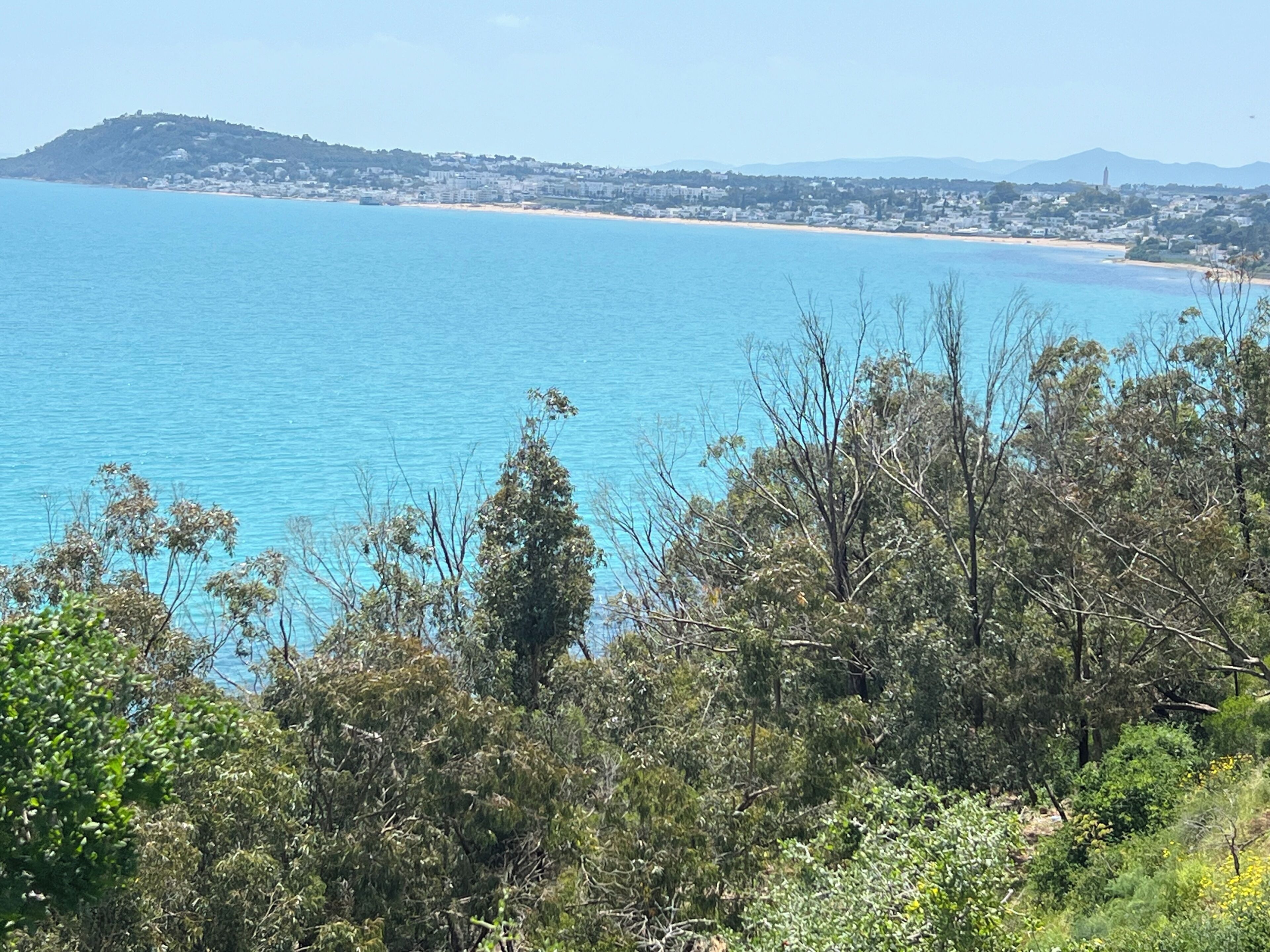 Eine Küstenlandschaft mit Blick auf das Meer, einen Strand und eine entfernte Stadtansicht.