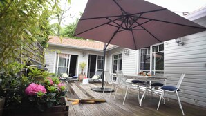 Eine Terrasse mit Tisch, Stühlen, einem großen Sonnenschirm und Topfpflanzen.