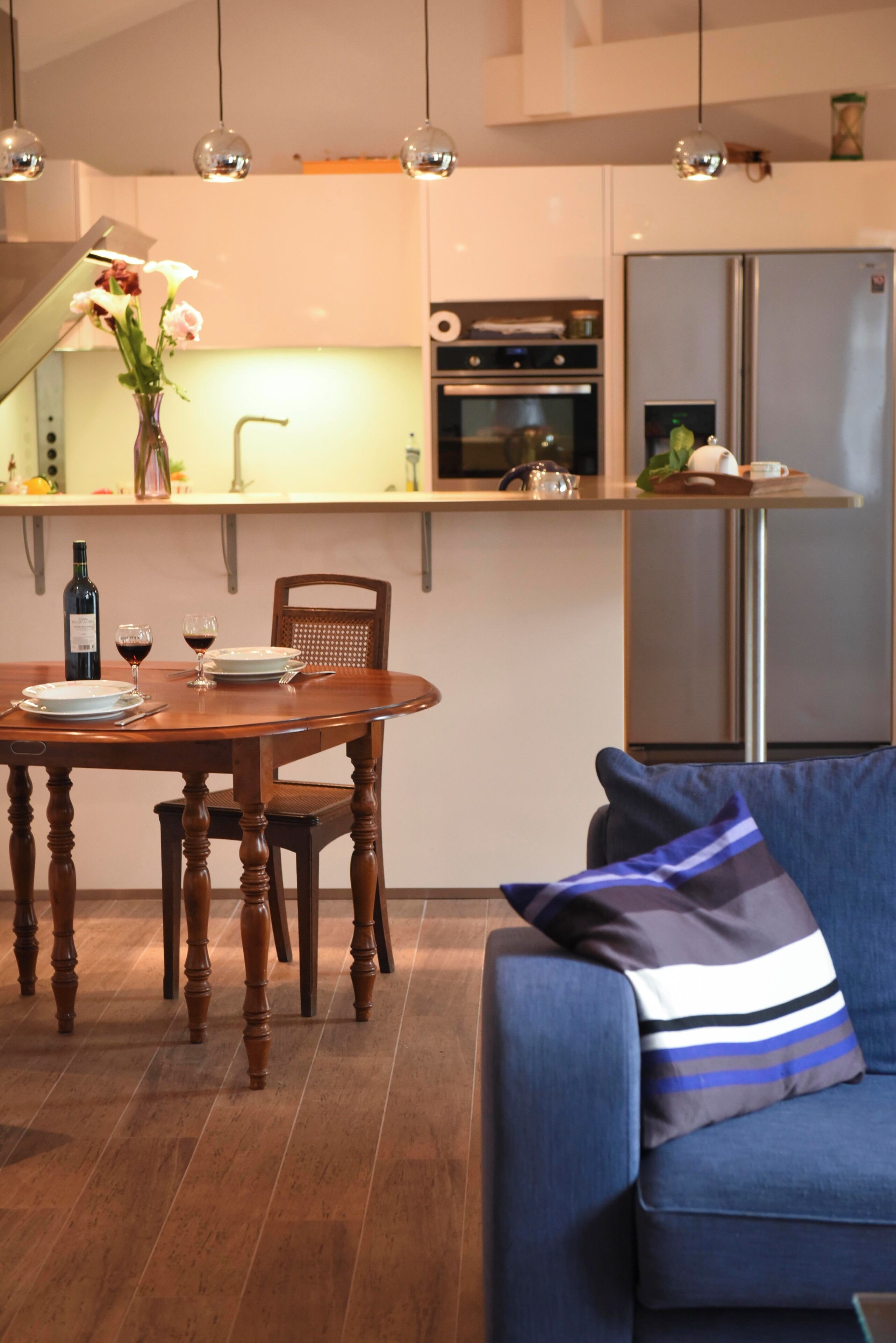 A modern kitchen with a dining table, chairs, and a sofa.