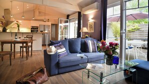 Ein modernes Wohnzimmer mit einer Couch, einem Glastisch und einem Essbereich mit einem Holztisch und Stühlen.