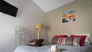 Ein ordentlich bezogenes Bett mit Hut, Lampe und Handtasche darauf.