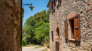 A narrow cobblestone street with stone buildings, a gravel path, and a clear blue sky.
