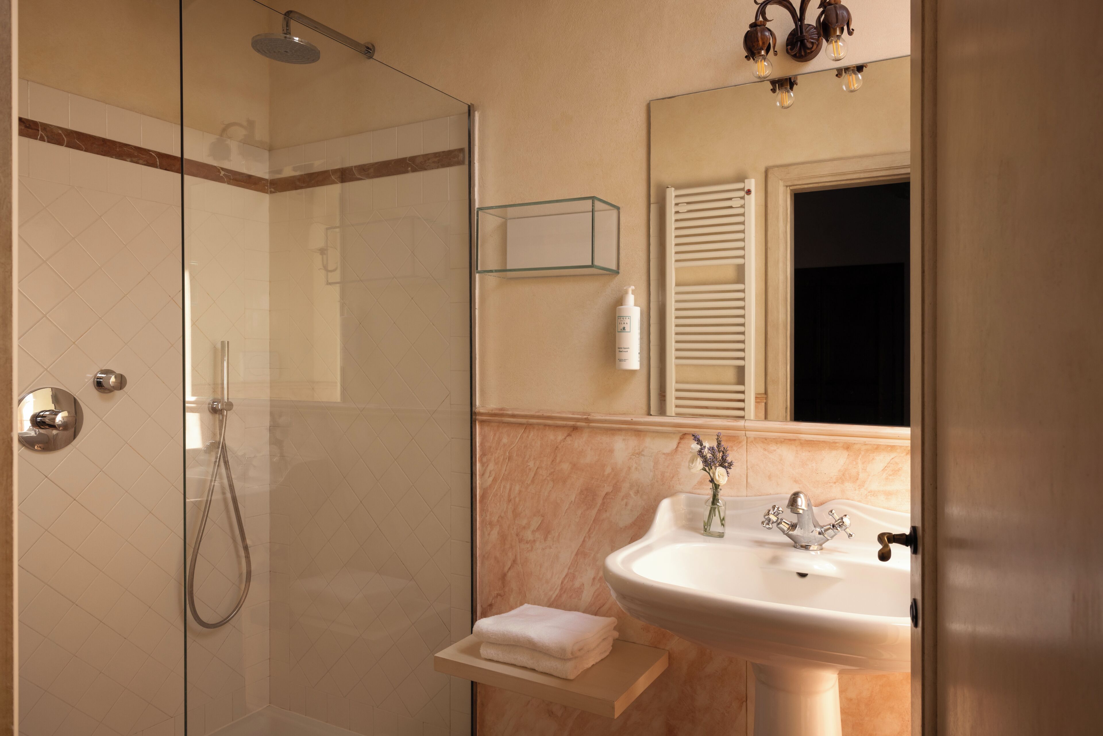 A bathroom with a glass shower enclosure, a white sink with a single faucet, and a mirror above the sink.