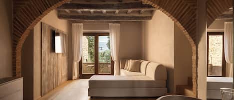 Una habitación acogedora con piso de madera, un sofá, una mesa con un vaso y vistas a través de una ventana.
