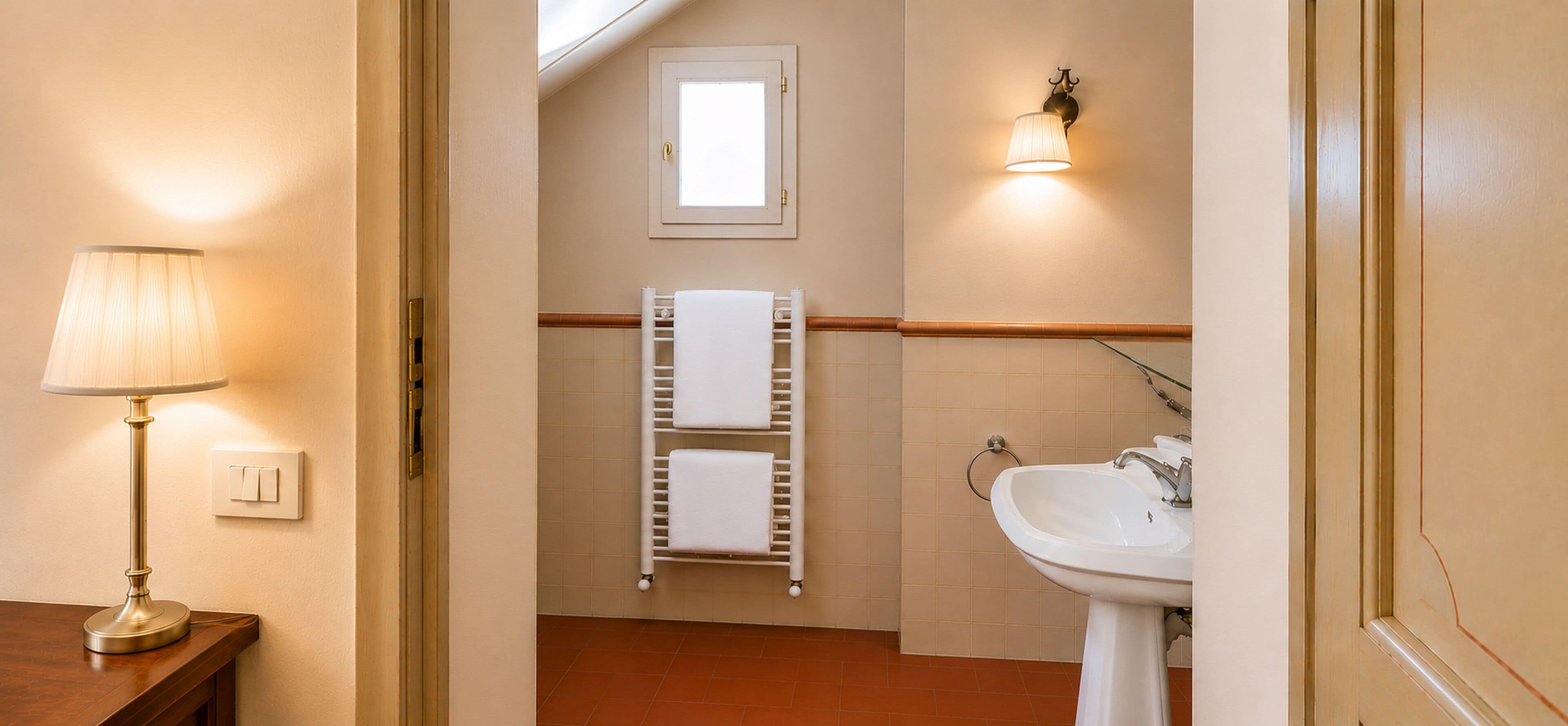 A hotel bathroom with a sink, towel rack, and a lamp.