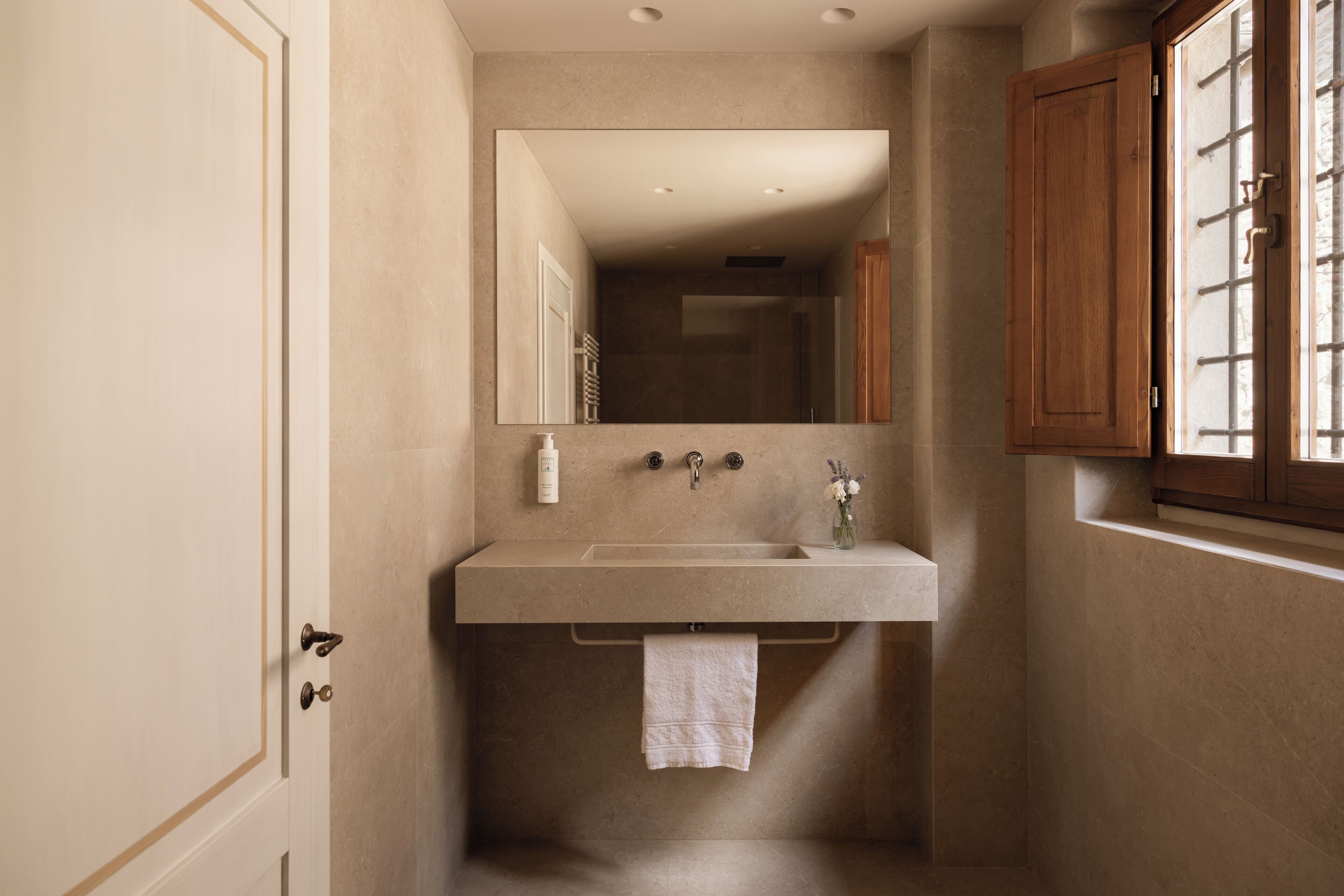 A bathroom with a sink, mirror, towel rack, and wooden cabinets.