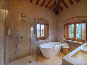 A modern bathroom with a glass-enclosed shower, a freestanding bathtub, and a vanity with a sink.