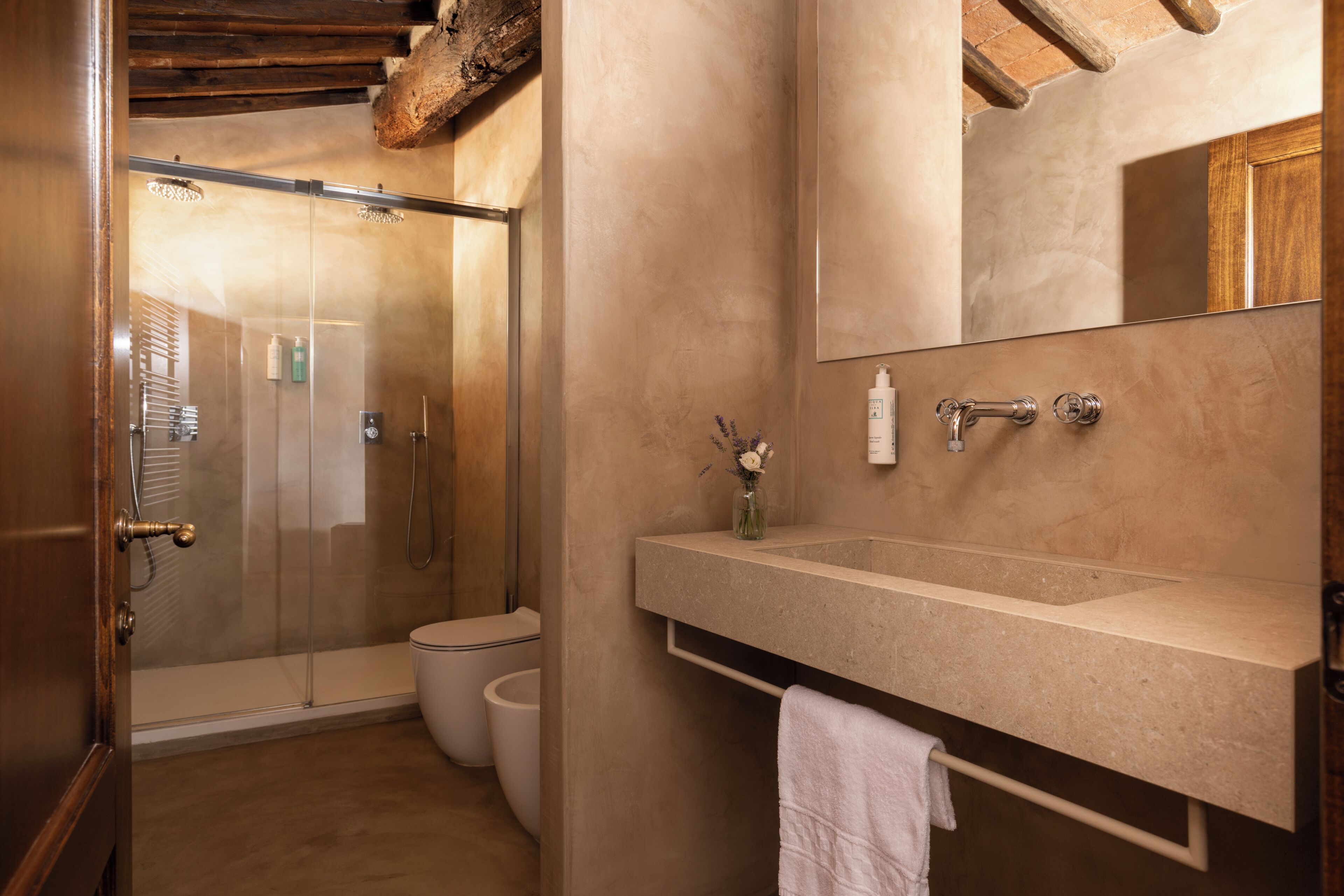 Een badkamer met een glazen douchecabine, toilet, wastafel met spiegel en een handdoekhouder.