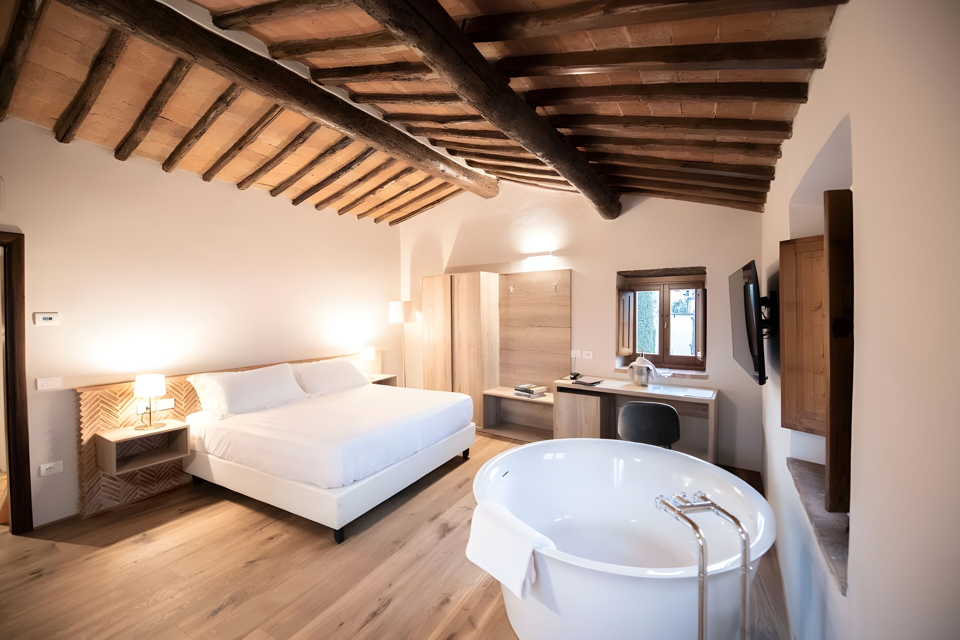 Un dormitorio con cama, mesita de noche, lámpara y una bañera grande.