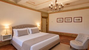 A bedroom with a large bed, bedside lamps, a chair, and a chandelier. - Villa Barberino (Meleto)