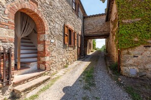 Un estrecho sendero de piedra que lleva a un edificio rústico con una escalera y una puerta arqueada.