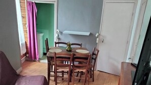 Ein Zimmer mit einem Holzesstisch, vier Stühlen, einem violetten Sofa und einem Holzschrank.