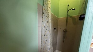 Eine Dusche mit Handbrause, einer Duschvorhang mit Punkten und einer gefliesten Wand.
