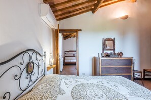 Een slaapkamer met een bed, een dressoir, een spiegel en een houten plafond.