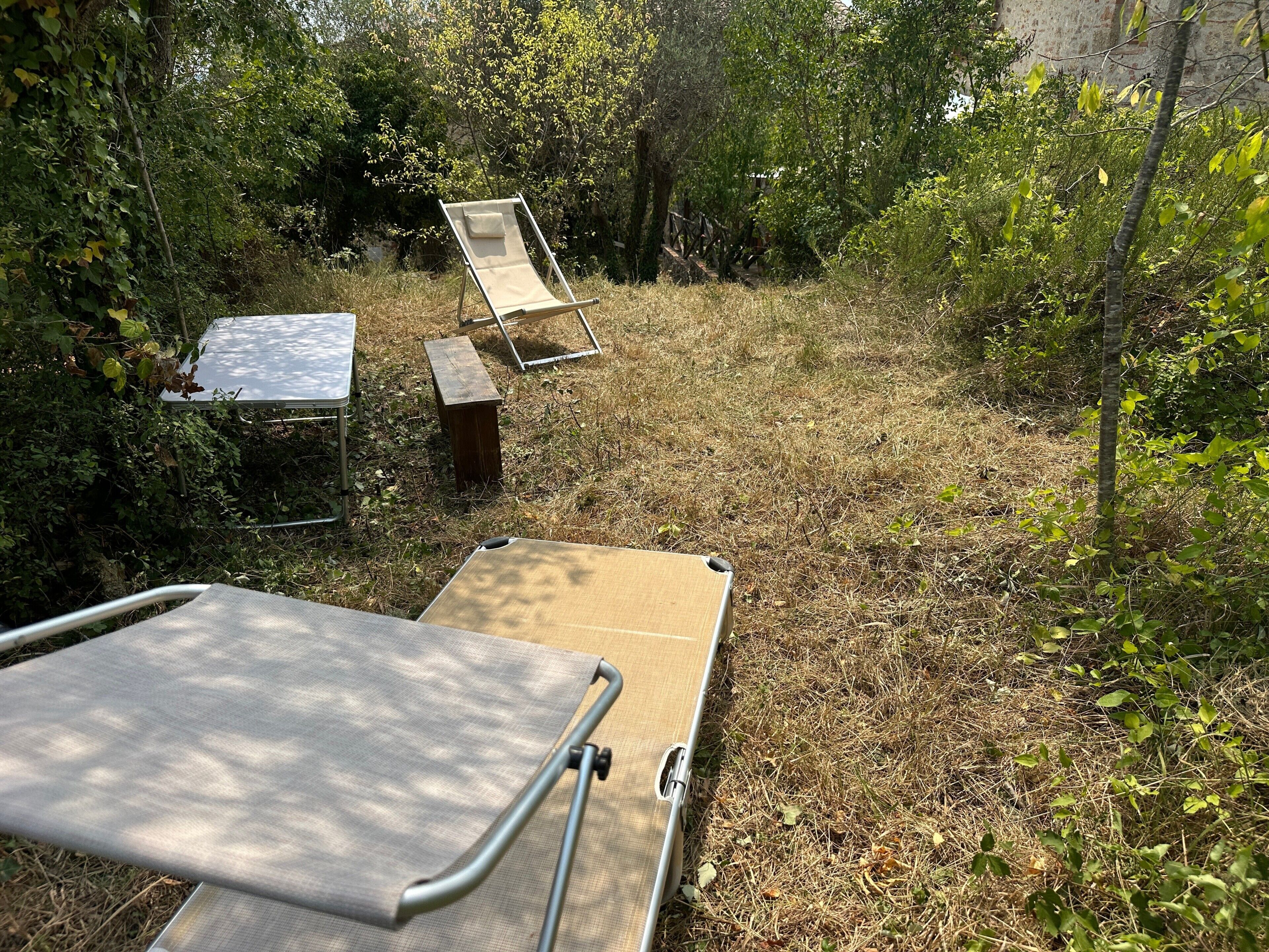 A garden with a metal table, a wooden bench, and a metal chair.