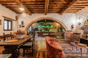 Un interno rustico con un tavolo da pranzo in legno, sedie, un divano, un biliardo e un camino.