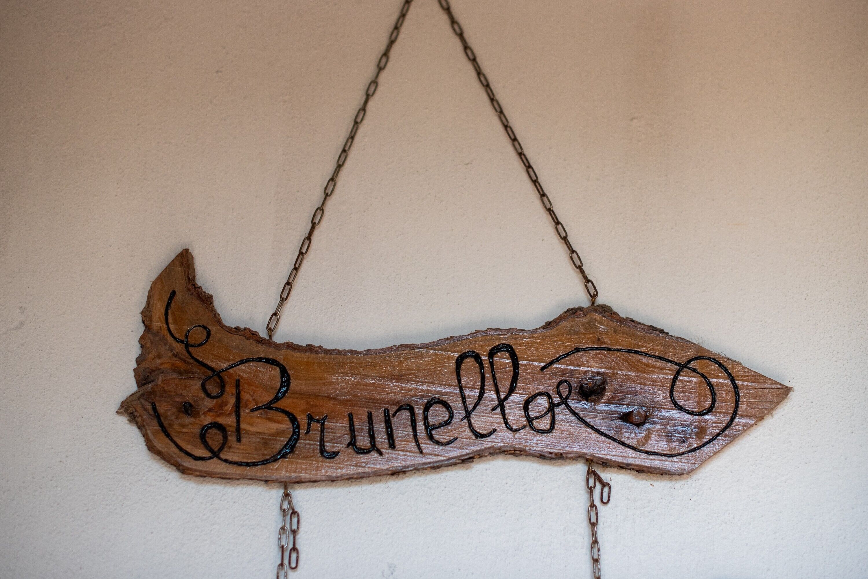 Een houten bord met de naam 'Brunello' bevestigd aan een muur.