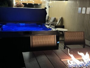 Un jacuzzi con luz azul, una chimenea y sillas de mimbre.