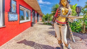 A red building with a tiled walkway, a statue, and a sign indicating 'Isla de la Palma.' - Hotel Rural Los Piratas Los Tilos 2 – Apartment with sea view & terrace (Tijarafe)