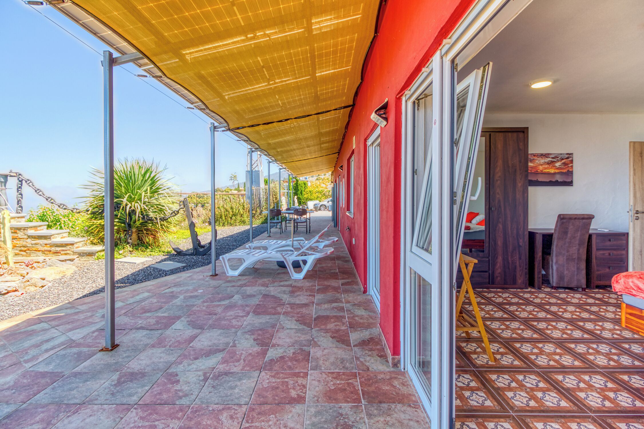 Un espace extérieur abrité avec une terrasse, un bâtiment rouge et une vue sur la mer.