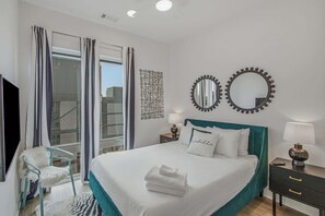 A hotel room with a bed, two bedside tables, a chair, a TV, and a window with curtains. - 2 Mi to Downtown Nashville・Spacious Chic Condo (Nashville)