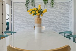 A dining table with a wooden vase centerpiece, teal chairs, and a cloud-patterned wall. - 2 Mi to Downtown Nashville・Spacious Chic Condo (Nashville)