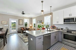 Una cocina moderna con una isla central, electrodomésticos de acero inoxidable y una zona de comedor con sofá y mesa.