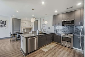A modern kitchen with stainless steel appliances, a central island, and pendant lighting. - Stylish & Contemporary 5th floor Condo, Sleeps 10 (Nashville)