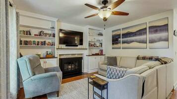 A living room with a fireplace, a television, a bookshelf, and a sofa.