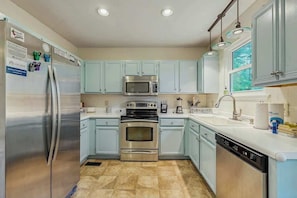 Una cocina con electrodomésticos de acero inoxidable, armarios azul claro y lavavajillas.