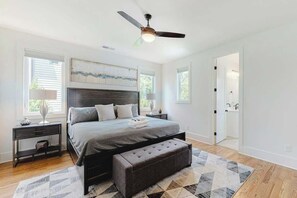 A bedroom with a bed, nightstands, a bench, a ceiling fan, and a window. - Stunning new w skyline views, rooftop deck, firepit, game room, shuffleboard, AC (Nashville)