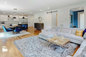 A modern living room with a sofa, coffee table, and blue chairs. - Stunning new w skyline views, rooftop deck, firepit, game room, shuffleboard, AC (Nashville)