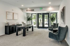 A modern interior with a reception desk, seating area, and large glass doors leading outside. - Modern end-unit condo with balcony, AC, washer & dryer, seasonal pool (Nashville)