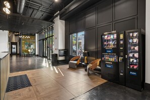 Un hall d’entrée moderne doté d’un distributeur automatique, d’un espace salon et offrant une vue sur la rue.