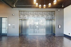 A spacious lobby with a modern design, featuring a patterned wall, elevators, and a polished floor. - Music City Condo・Mins to Broadway W Rooftop Lounge (Nashville)