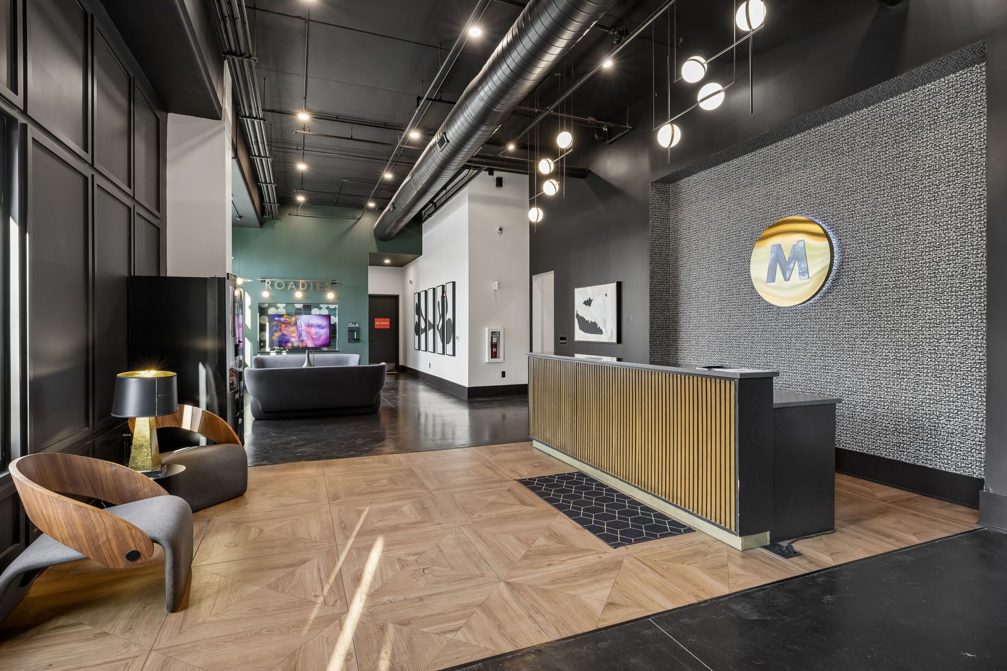 A reception area with a reception desk, a waiting area with chairs, and a wall with a textured pattern and a logo.