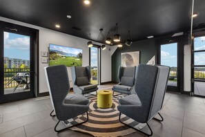 A modern lounge area with grey upholstered chairs, a yellow ottoman, and a large painting of a golf course. - Music City Condo・Mins to Broadway W Rooftop Lounge (Nashville)