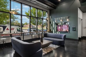 A modern interior with a seating area, a large window with a view of the street, and a wall-mounted TV displaying a music video. - Music City Condo・Mins to Broadway W Rooftop Lounge (Nashville)