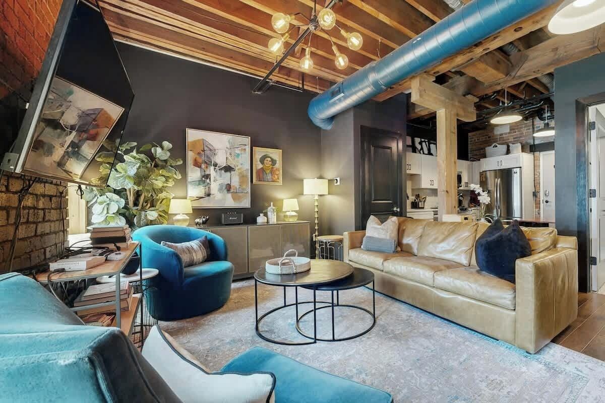 A modern living room with a sofa, armchairs, a coffee table, and a fireplace.