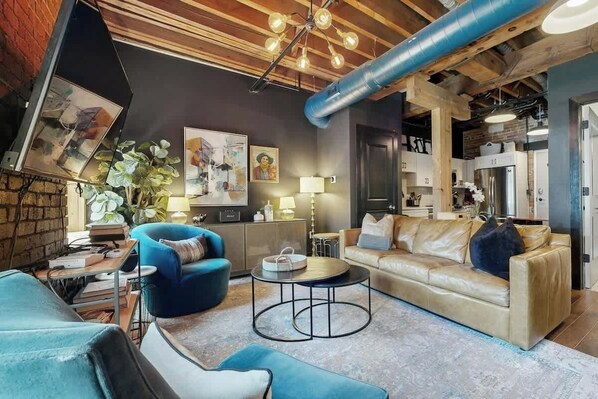 A modern living room with a sofa, armchairs, a coffee table, and a fireplace. - Luxe, historical condo home near downtown with WD, pool, outdoor lounge & grill (Nashville)