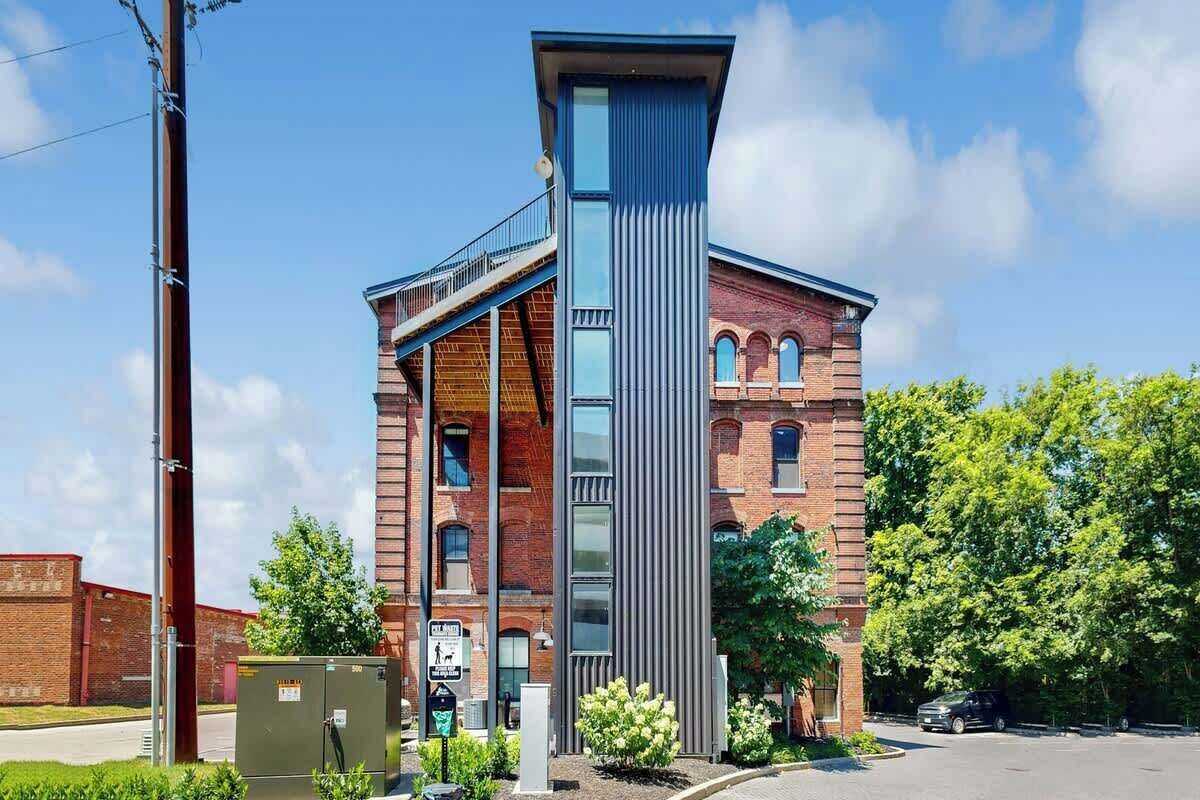 A modern building with a prominent vertical structure, a brick facade, and a clear sky.