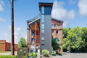A modern building with a prominent vertical structure, a brick facade, and a clear sky. - Luxe, historical condo home near downtown with WD, pool, outdoor lounge & grill (Nashville)