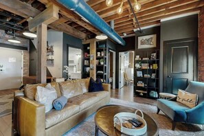 A modern living room with a leather sofa, a round coffee table, and a blue armchair. - Luxe, historical condo home near downtown with WD, pool, outdoor lounge & grill (Nashville)